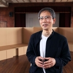 震災学習で使う段ボールベッドの前で、１万日の歩みを振り返る山住勝利さん＝神戸市長田区二葉町７、ふたば学舎講堂（撮影・鈴木雅之）