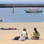 遊泳自粛中の海辺で日光浴などをする人たち＝２０２０年８月、神戸市須磨区、須磨海岸