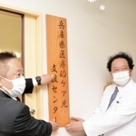 兵庫県医療的ケア児支援センターの看板を掲げる常石秀市・医療福祉センターきずな院長（右）と生安衛・県福祉部長＝加西市若井町