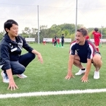 環境に配慮した人工芝の感触を確かめながら、斎藤元彦知事（左）と笑顔で話す岡崎慎司選手＝神戸市西区平野町印路