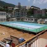 運動場いっぱいに設置されゆく仮設プール。３年ぶりの登場となる＝神戸市灘区箕岡通１、美野丘小学校（撮影・長嶺麻子）