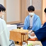 立会人の小林健二・九段（右）から封じ手を示される藤井聡太王位。左は豊島将之九段＝２９日午前、愛知県犬山市、ホテルインディゴ犬山有楽苑