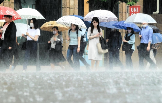 たたきつけるような雨の中を歩く人たち＝１２日午前、神戸市中央区（撮影・鈴木雅之）