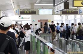 調整中の案内が表示されたホームで車両の到着を待つ乗客ら＝５日午前１０時、神戸市東灘区、六甲ライナー住吉駅（撮影・長嶺麻子）
