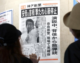安倍元首相が銃撃されたことを伝える張り出し号外。通りがかりの人たちが真剣な表情で見つめる＝８日午後２時１分、神戸市中央区東川崎町１、デュオこうべ（撮影・長嶺麻子）