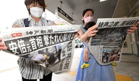 安倍元首相が撃たれ心肺停止となったことを伝える号外を手に取る通行者たち＝８日午後２時２８分、神戸市中央区、ＪＲ三ノ宮駅前（撮影・秋山亮太）