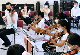 ワークショップで神戸市室内管弦楽団の井上隆平（左）からバイオリンを教わる子どもら＝神戸市中央区橘通３