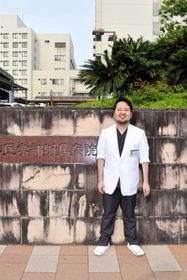 神戸大病院の前に立つ市川裕太さん。かつて入院した病棟で、自身と同じ腎臓病の子どもたちを診療する夢をかなえた＝２０２２年５月、神戸市中央区