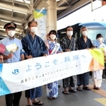 城崎温泉駅を出発する銀河の前で撮影する城崎温泉観光大使や登日幸治但馬県民局長（右から２人目）＝１日午後、豊岡市城崎町、ＪＲ城崎温泉駅