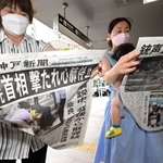 安倍元首相が撃たれ心肺停止となったことを伝える号外を手に取る通行者たち＝８日午後２時２８分、神戸市中央区、ＪＲ三ノ宮駅前（撮影・秋山亮太）