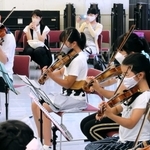 ワークショップで神戸市室内管弦楽団の井上隆平（左）からバイオリンを教わる子どもら＝神戸市中央区橘通３