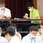 集計された投票用紙の束を確認する開票立会人。２４歳の介護士武田詩音さん（右奥）は「投じられた票に触れることで、その重みを実感した」＝１０日午後１１時２４分、猪名川町紫合
