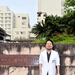 神戸大病院の前に立つ市川裕太さん。かつて入院した病棟で、自身と同じ腎臓病の子どもたちを診療する夢をかなえた＝２０２２年５月、神戸市中央区