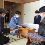 「お～いお茶杯第６３期王位戦」７番勝負の第３局で、立会人の福崎文吾九段（左）から封じ手を示される藤井聡太王位（右）。奥は豊島将之九段＝２１日午前、神戸市北区有馬町、有馬温泉の旅館「中の坊瑞苑」（撮影・鈴木雅之）