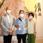 来場１万人目となり、石井嘉彦副館長（左）から記念品を贈られた永田敏彦さんと由美子さん夫婦＝神戸市東灘区向洋町中２