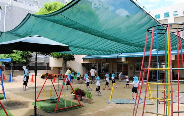 遮光ネットの下で遊ぶ園児たち＝神戸市長田区神楽町２、神楽こども園