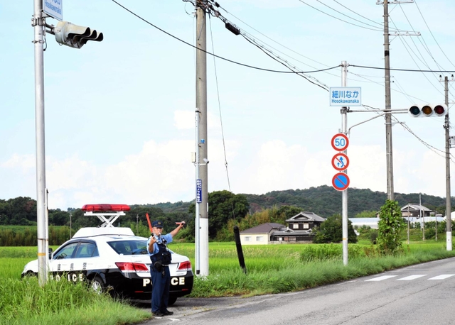 信号の消えた交差点で、手信号で交通整理をする警察官＝５日午後、三木市細川町細川中
