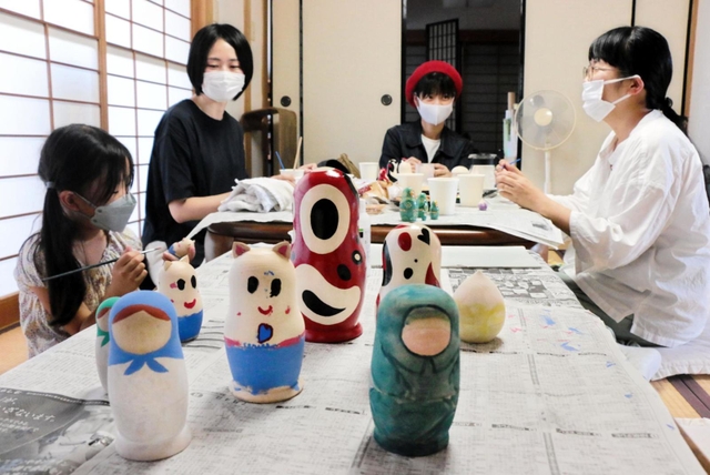 ロシア出身の夫を持つ平野陽子さん（左から２人目）らが企画した「国境なきマトリョーシカ展」に向け、マトリョーシカに絵付けをする画家ら＝神戸市兵庫区五宮町