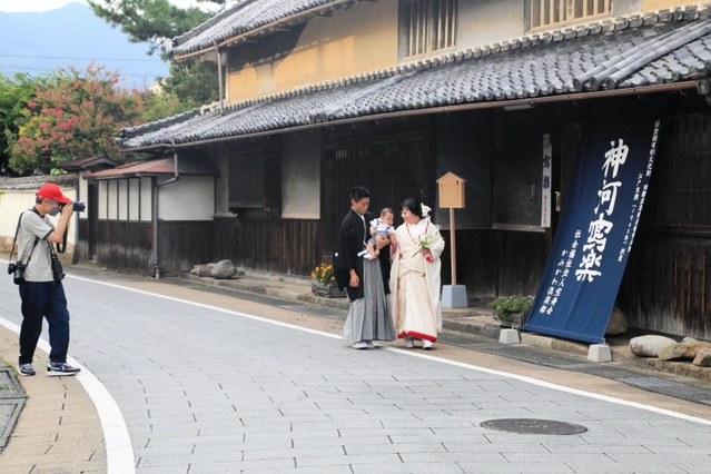 国登録有形文化財「旧難波酒造」の前で写真を撮ってもらう吉川さん夫妻＝神河町中村