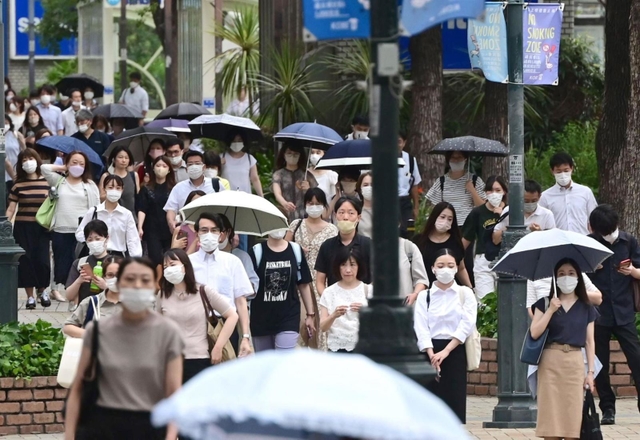 盆が明け、厳しい残暑の中、出勤する人たち＝１６日朝、神戸市中央区