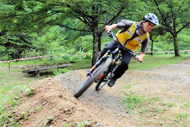 広場跡にできた初心者向けのマウンテンバイク専用コース。残土を運んで整備した。車体を大きく傾けて試走する＝養父市大屋町明延
