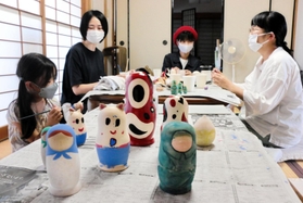 ロシア出身の夫を持つ平野陽子さん（左から２人目）らが企画した「国境なきマトリョーシカ展」に向け、マトリョーシカに絵付けをする画家ら＝神戸市兵庫区五宮町