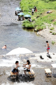 夢前川に足首まで漬かりながら食事を楽しむ家族連れら＝姫路市夢前町山之内