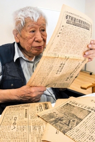 太平洋戦争前後に発行された新聞を読んで記憶をたどる吉龍資雄さん＝芦屋市潮見町