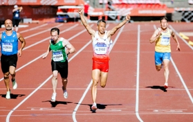陸上の世界マスターズ選手権男子５０～５４歳の部２００メートル決勝を制し、両腕を突き上げる赤堀弘晃さん（右から２人目）＝７月３日、フィンランド・タンペレ（北原基行さん撮影）