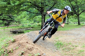 広場跡にできた初心者向けのマウンテンバイク専用コース。残土を運んで整備した。車体を大きく傾けて試走する＝養父市大屋町明延