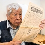 太平洋戦争前後に発行された新聞を読んで記憶をたどる吉龍資雄さん＝芦屋市潮見町
