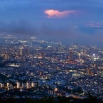 薄暮の中で輝く神戸の街。大阪方面の空では稲妻がまばゆい光を放っていた＝１６日夜、神戸市灘区摩耶山町、掬星台（撮影・秋山亮太）