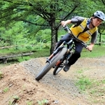 広場跡にできた初心者向けのマウンテンバイク専用コース。残土を運んで整備した。車体を大きく傾けて試走する＝養父市大屋町明延