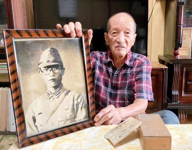 父恒男さんの遺影を手に、「戦犯遺族」としての思いを語る寺越脩さん＝西脇市岡崎町