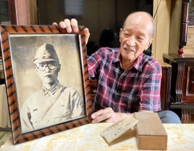 父恒男さんの遺影を手に、「戦犯遺族」としての思いを語る寺越脩さん＝西脇市岡崎町