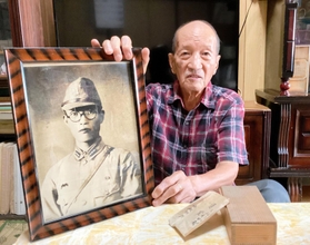 父恒男さんの遺影を手に、「戦犯遺族」としての思いを語る寺越脩さん＝西脇市岡崎町