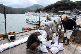 台風１１号の接近に備え、土のうを作って岸壁沿いに並べる作業員ら＝９月６日、兵庫県香美町香住区沖浦
