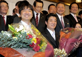 大阪府知事、大阪市長ダブル選を制し、花束を受け取った橋下徹氏（左）と松井一郎氏。堺市議だった馬場伸幸氏（後列右から２人目）も笑顔を見せた＝２０１１年１１月２７日夜、大阪市北区