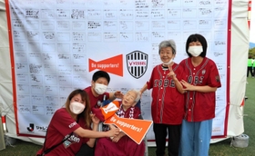 エールを寄せた１０７歳の竹本繁野さん（中央）を囲む「オリンピア兵庫」の利用者や職員ら＝神戸市兵庫区、ノエビアスタジアム神戸