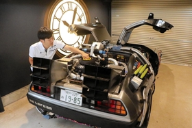 自宅の車庫でデロリアンを点検する津和さん。壁掛けの時計は、劇中で登場する時計台をモチーフに自作したという＝神戸市東灘区