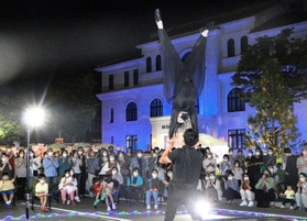 路上パフォーマンスや夜市でにぎわう豊岡市役所前＝２５日夜、豊岡市中央町（撮影・丸山桃奈）