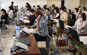 オンラインでの登録申請を受け、内容を確認する「陽性者登録支援センター」の担当者ら＝２６日午前、神戸市中央区東川崎町１