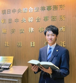 胸には弁護士バッジ。裁判などに日々向き合う＝大阪市北区（本人提供）
