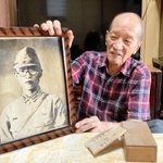 父恒男さんの遺影を手に、「戦犯遺族」としての思いを語る寺越脩さん＝西脇市岡崎町