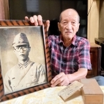 父恒男さんの遺影を手に、「戦犯遺族」としての思いを語る寺越脩さん＝西脇市岡崎町