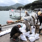 台風１１号の接近に備え、土のうを作って岸壁沿いに並べる作業員ら＝９月６日、兵庫県香美町香住区沖浦