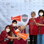 エールを寄せた１０７歳の竹本繁野さん（中央）を囲む「オリンピア兵庫」の利用者や職員ら＝神戸市兵庫区、ノエビアスタジアム神戸