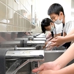 センサー式の自動水栓に手を伸ばす小学生ら＝西須磨小学校（撮影・秋山亮太）
