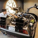 自宅の車庫でデロリアンを点検する津和さん。壁掛けの時計は、劇中で登場する時計台をモチーフに自作したという＝神戸市東灘区