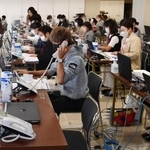 オンラインでの登録申請を受け、内容を確認する「陽性者登録支援センター」の担当者ら＝２６日午前、神戸市中央区東川崎町１